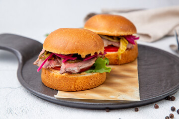 hot burgers with lettuce and vegetables on a wooden board