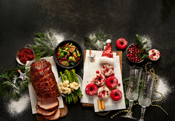 Baked ham with vegetablesand donuts on dark background. Christmas food