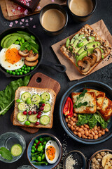 Tasty food with avocado toast, vegetables, eggs on dark background. Helthy breakfast concept