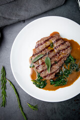 steak in gravy with herbs on it on a white plate