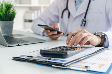 Doctor physician calculate medical healthcare fee costs and revenue, Practitioner using calculator at Clinic.