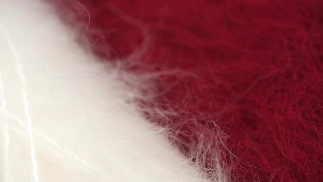 closeup of fluffy natural wool in red and white for knitting and crocheting, rotation. skeins of mohair for winter warm, cozy sweaters, mittens, hats, handmade socks. macro.