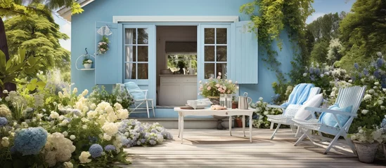 Poster de jardin Jardin Lovely blue house with beautiful garden and farmhouse vibes Terrace with wicker baskets greenery and white furniture Backyard with gardening tools