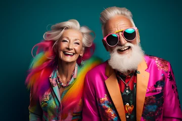 Gordijnen Happy senior retired couple in colourful neon clothes, isolated on bluebackground © sam
