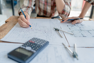 multi ethnic engineer brainstorming and measuring for cost estimating on blueprint and floor plan drawings about design architectural and engineering for houses and buildings