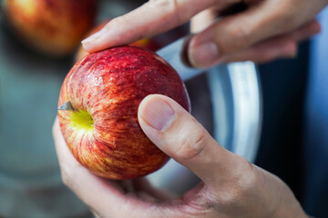 woman hand is cleaning red apple in bucket of water, closed up shot