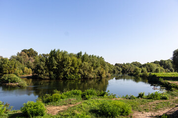 Fototapeta na wymiar Landscape with river, trees and blue sky