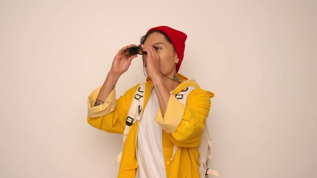 Young Asian tourist man looking through binoculars on white background.