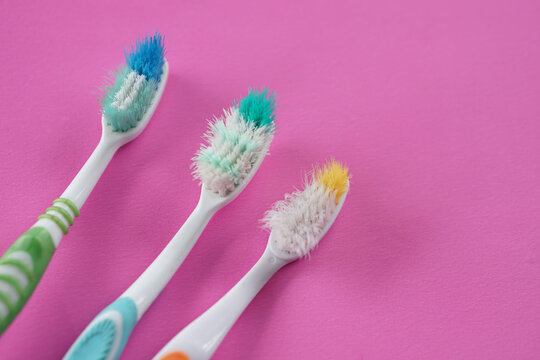 Three used, old toothbrushes on pink background. Concept, tool for brush teeth. Need to change new one from long time using toothbrush for efficiency of dental cleaning.                               