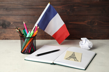 Flag of France with stationery on table near dark wooden wall