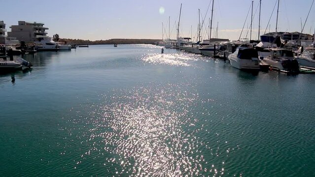 On beautiful Summer&rsquo;s day a Paddle boarder rows on water in a marina 