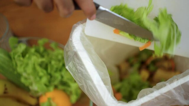 Ecology compost supply kitchen waste sorting waste vegetable peels from cutting board to recycle composter environmentally friendly. Man throws leftover fruit peel and vegetables reduce zero waste.