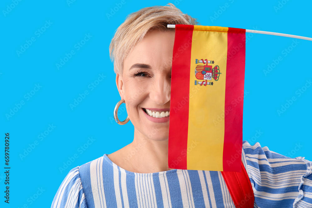 Poster Happy mature woman with flag of Spain on light blue background