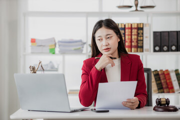 Portrait of young Asian lawyer working and hammer, tablet, laptop in front, justice and legal concept