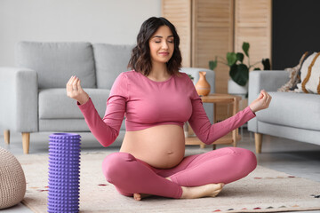 Sporty pregnant woman meditating at home