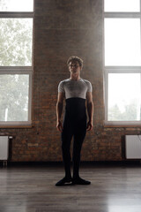 Fototapeta na wymiar Full-length portrait of handsome athletic ballet dancer in studio room