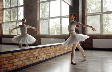 Beautiful young ballerina training classic ballet in studio with huge mirror - obrazy, fototapety, plakaty
