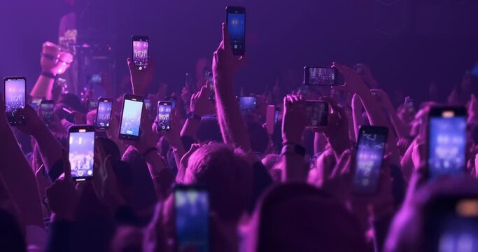 Audience silhouette filming video, photo of music band in stage. Blue phones screens with entertainment event in crowd hands. live festival in night club. Happy people take videos of show performance