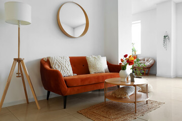 Interior of stylish living room with cozy sofa, mirror and tulip flowers on coffee table