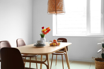 Interior of light dining room with tulip flowers on table