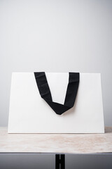 White paper bag with black fabric handles on a marble table, white background. Mockup, brand mock up - 659783336