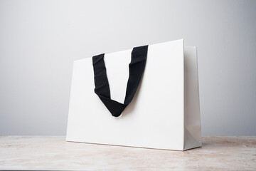 White paper bag with black fabric handles on a marble table, white background. Mockup, brand mock up - 659783530