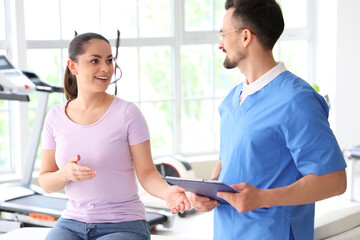 Male physiotherapist working with young woman in rehabilitation center