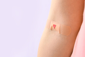 Woman with applied medical patch on lilac background, closeup. World Blood Donor Day