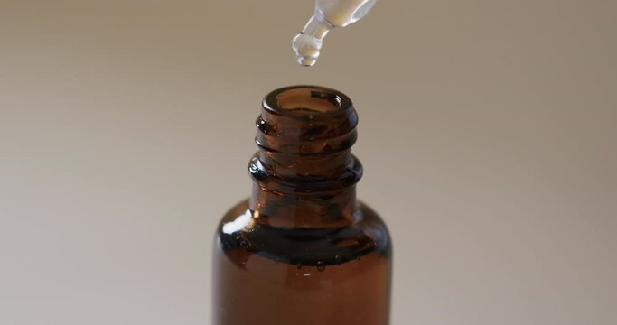 Video of make up bottle and pipette with clear drops and copy space on brown background