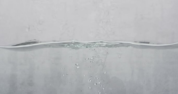 Video of beauty product bottle falling into water with copy space on white background
