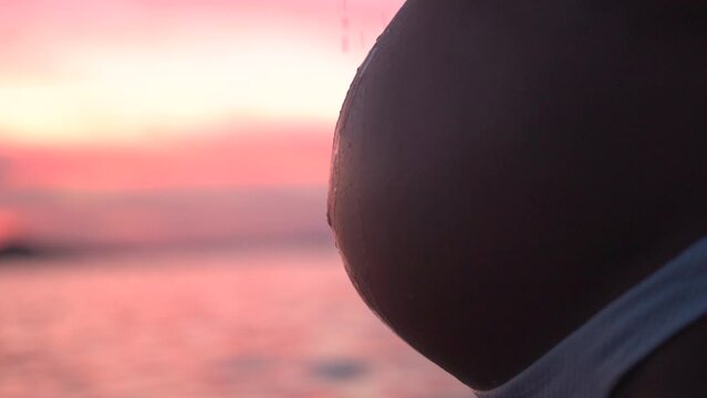 Pregnant belly baby, expecting mother belly at the beach during sunset relaxing