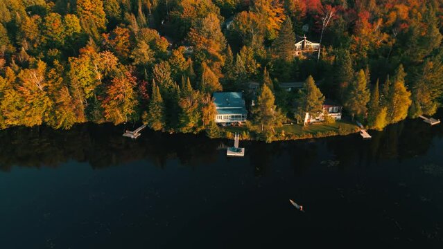 static drone shot over canadian lake during fall season with canoe approching the pontoon