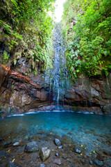 Scenic view of the lagoon at the end of the Levada das 25 Fontes hiking trail, where a waterfall cascades down the overgrown cliffs, Madeira, Portugal
