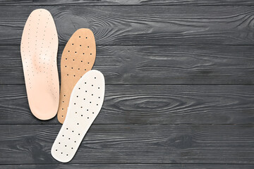 Different orthopedic insoles on dark wooden background