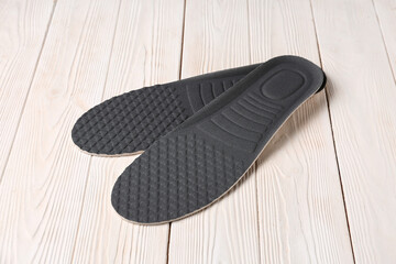 Pair of orthopedic insoles on light wooden background
