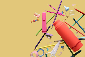 Flying pencil case and school stationery on beige background