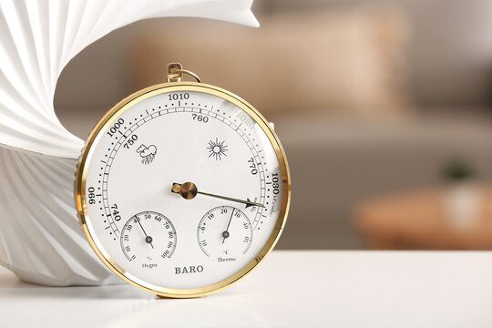 Aneroid barometer and decor on table in room, closeup
