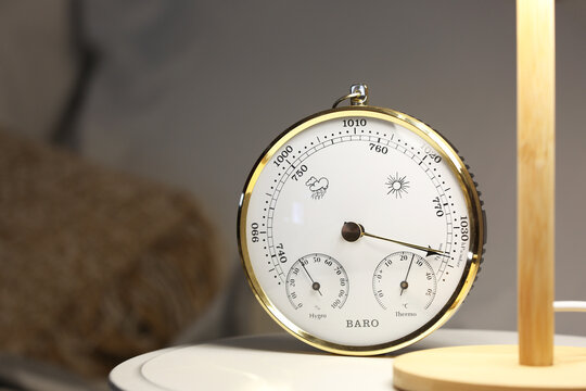 Aneroid barometer and glowing lamp on bedside table, closeup