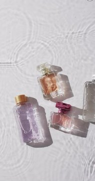 Vertical video of beauty product bottles in water with copy space on white background