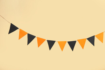 Obraz premium Garland made of paper flags for Halloween celebration on beige background