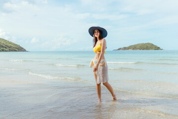 Fototapeta premium Beautiful woman in bikini happily walks on the beach at sunset