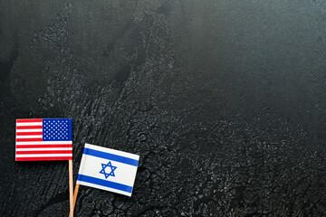USA Israel flags. Two small American and Israeli flags lie on black old texture background opposite...