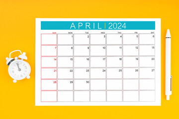 April 2024 calendar page and pen with alarm clock.