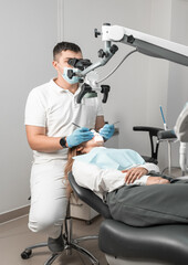 A dentist uses a microscope to treat a patient's teeth accurately and professionally. Dental treatment procedure under the supervision of a doctor and a microscope for higher efficiency.