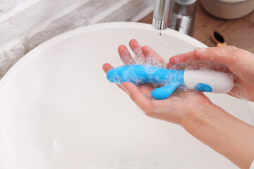 Woman washing vibrator over sink, closeup