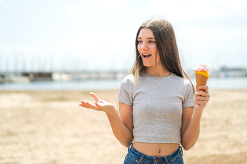 Teenager girl with a cornet ice cream at outdoors with surprise facial expression