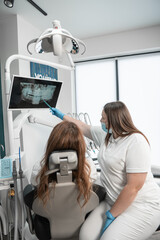 The dentist examines the results of a CT scan of the patient's mouth for an accurate diagnosis. Patients can expect the highest standard of dental care in a modern medical center.
