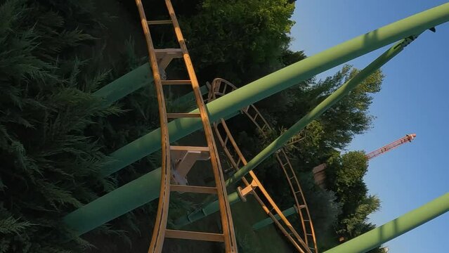 First person view of adrenaline twisting roller coaster at amusement park. Slow motion