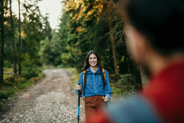 Couple enjoying a nature hike with backpacks and poles. Focus on Latin woman