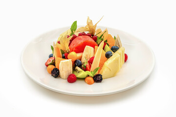 Mixed assorted fruits on white porcelain plate on wooden table